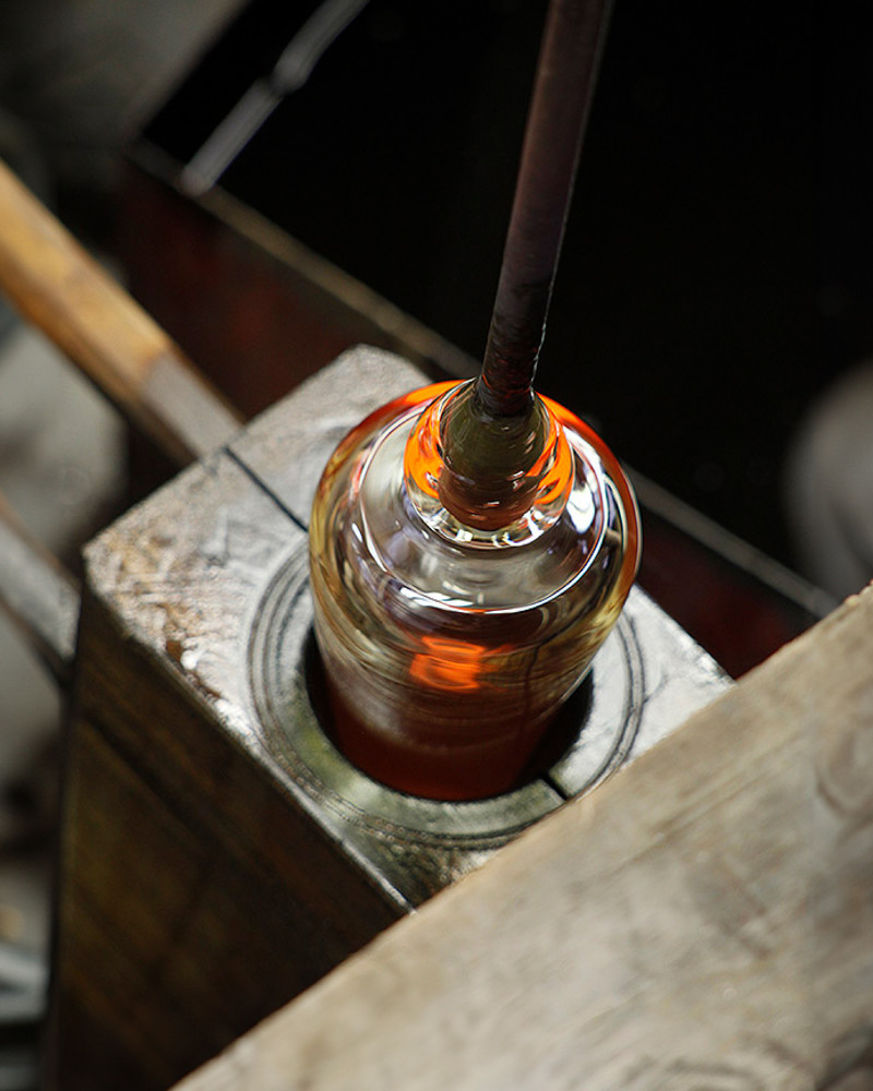During the manufacturing process, master glassmakers blow molten glass into a wooden mold under steady rotation, wherein the woo
