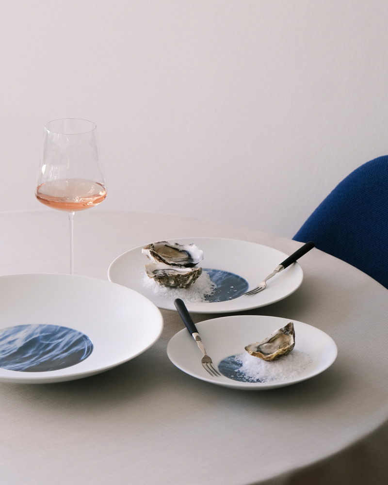 Three plates of Waves on a table with wine glass and oysters Large Coupe Plate together with small Coupe Plate